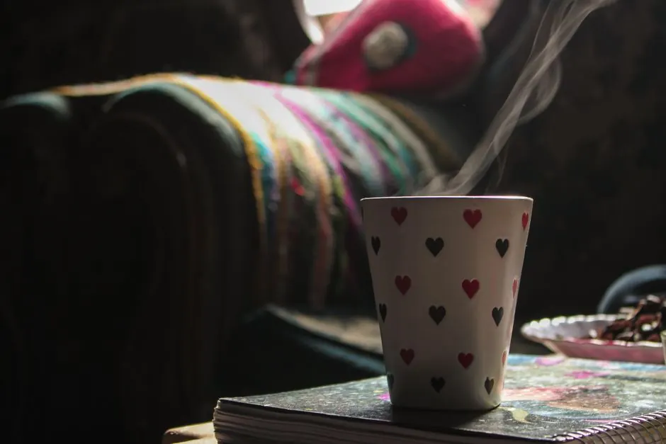 A heart-patterned coffee mug releasing steam in a cozy indoor setting, creating a warm atmosphere.